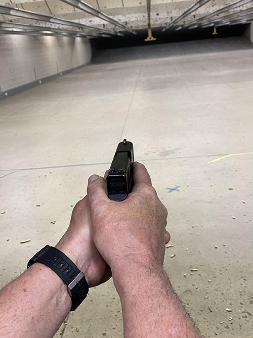 man holding pistol at a shooting range showing the proper muzzle discipline